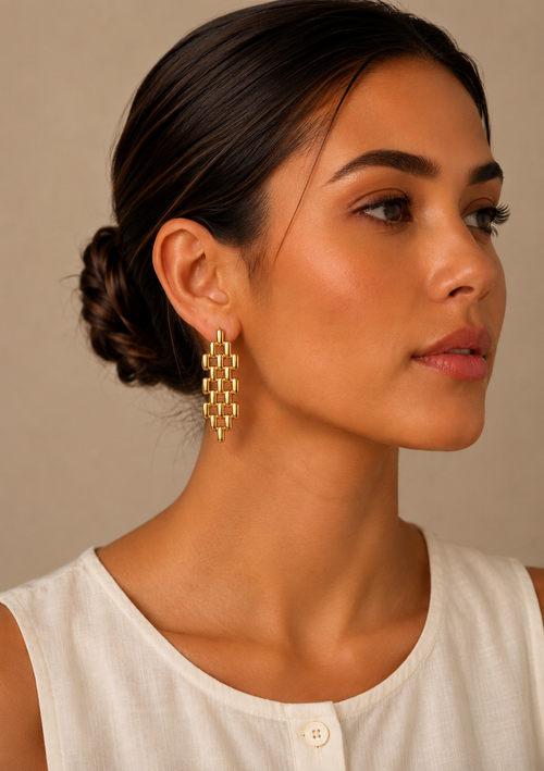 Adelïna, boucles d'oreilles pendantes en maille dorée articulée, portées par un mannequin au chignon bas