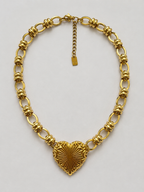 Collier Alina doré, cœur à rayons de soleil en relief, chaîne à maillons ovales et anneaux striés, packshot sur fond clair
