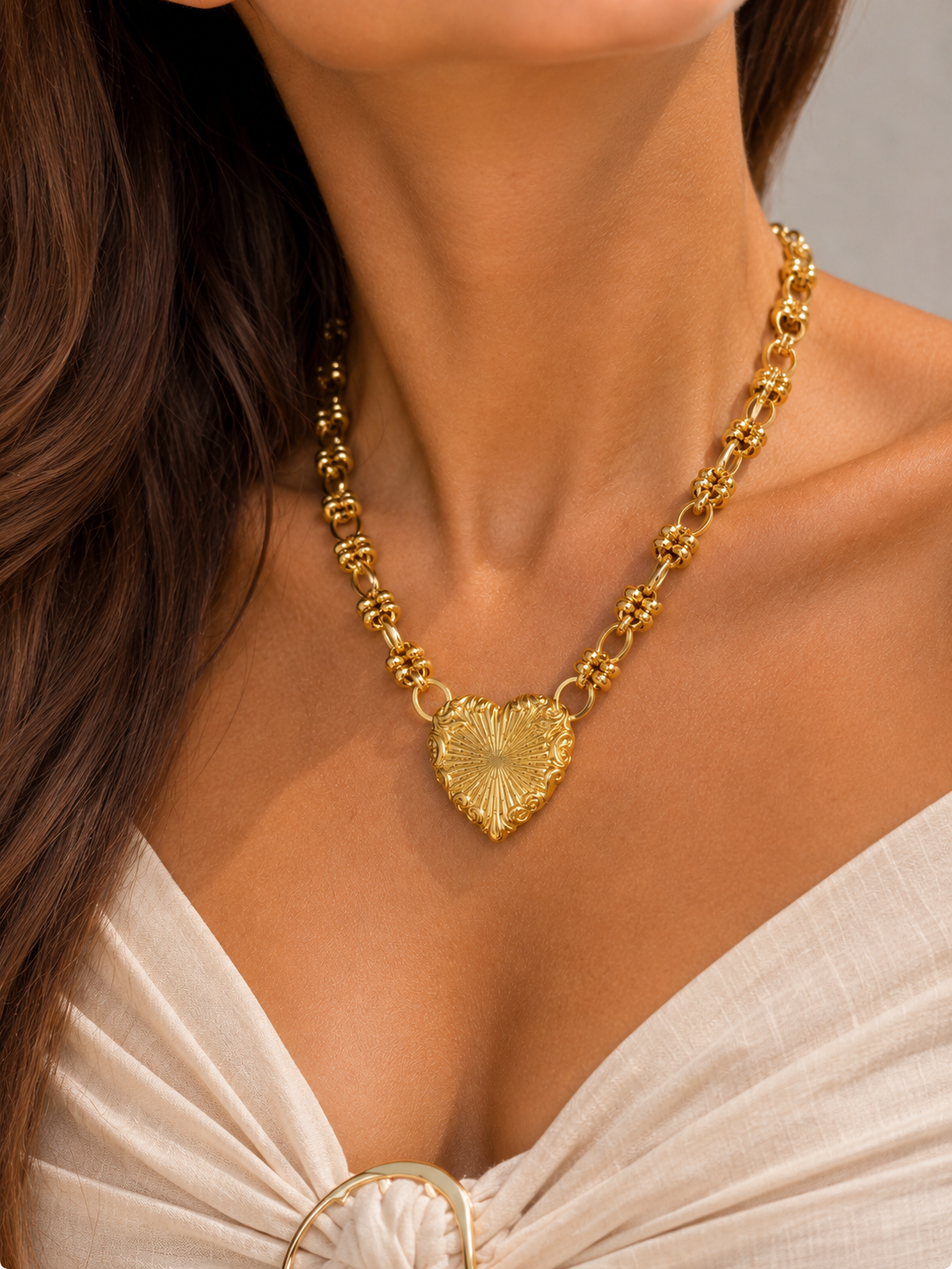 Collier Alina porté par un mannequin, cœur doré à rayons de soleil en relief sur chaîne à maillons ovales et anneaux striés