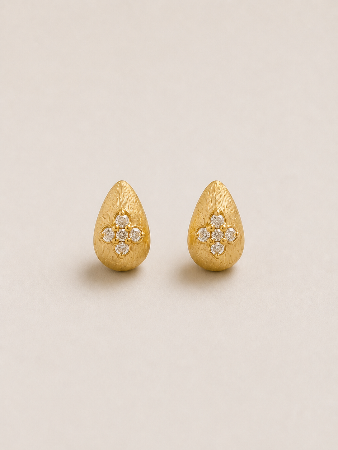 Anïa, puces d'oreilles gouttes dorées brossées ornées de quatre cristaux en croix, packshot sur fond beige