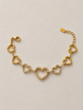 Athéna, bracelet de cœurs dorés ajourés sertis de zircons, packshot sur fond beige