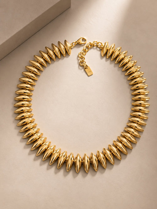 Alicia, collier doré à grains bombés, packshot sur fond beige