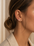Audace, mono-boucle dorée à zircon et double chaîne, portée sur deux piercings